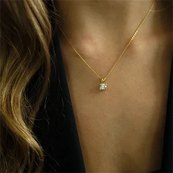En kvinde bærer en fin, gylden halskæde med en funklende labgrown diamant ved hendes hals.
