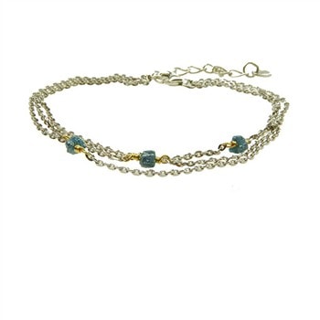 Elegant armbånd med tre kæder, blå-grønne rå diamanter og guldfarvede detaljer.