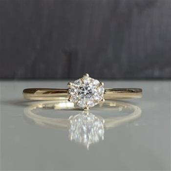 Ring i 14 karat guld med en 0,19 carat diamant i stjernefatning, reflekterer lys.